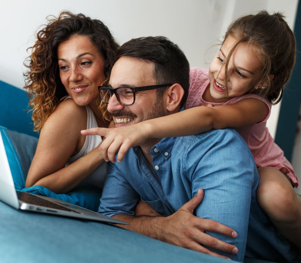A family of three are cuddled together looking at a laptop.