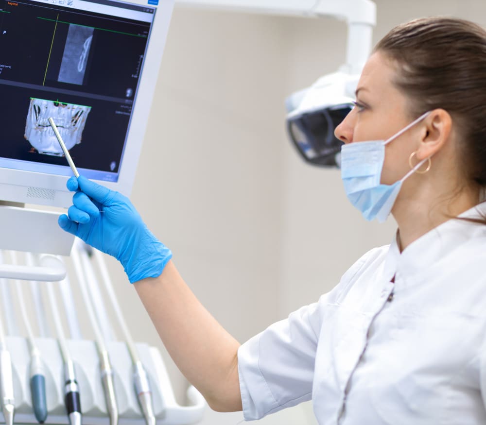 A clinician points to a scan of someone's jaw.