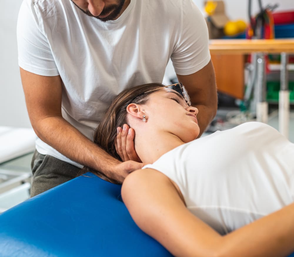 A physiotherapist works on someone's neck.