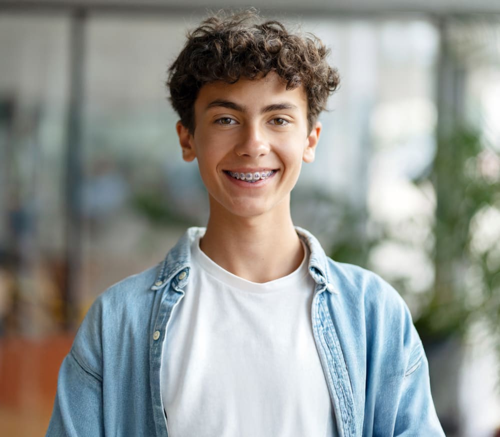 A teenage boy is smiling, showing off a mouth of braces.